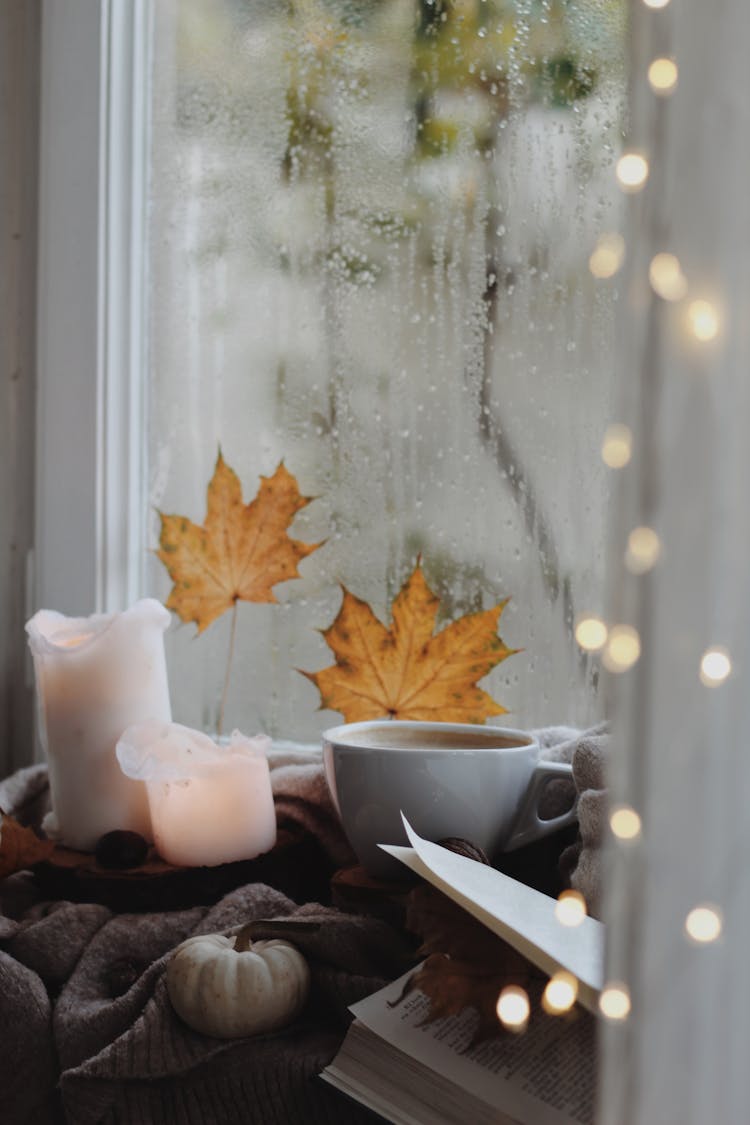 A Coffee Cup And Candles By A Window