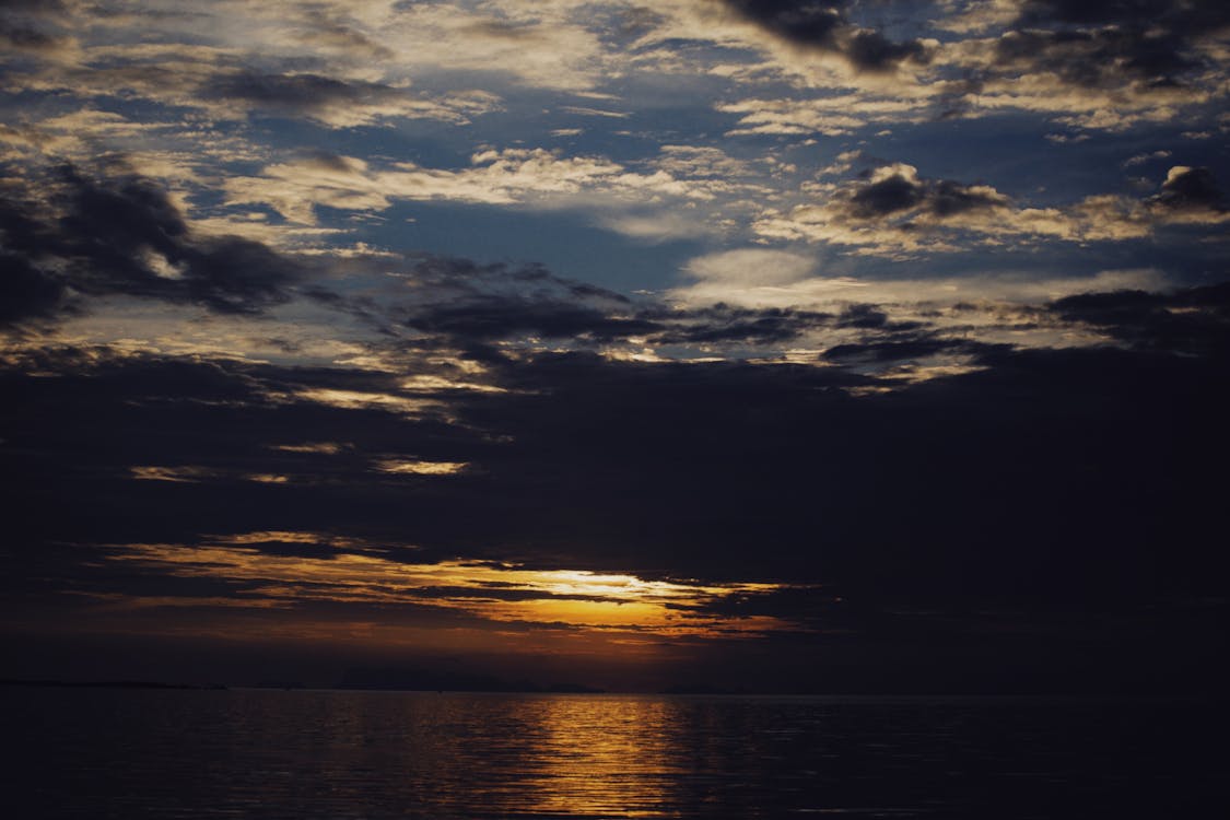 Body of Water Under Dark Clouds during Sunset