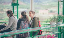 三名年轻女子背着背包，在户外被盆栽环绕，享受着轻松的一天