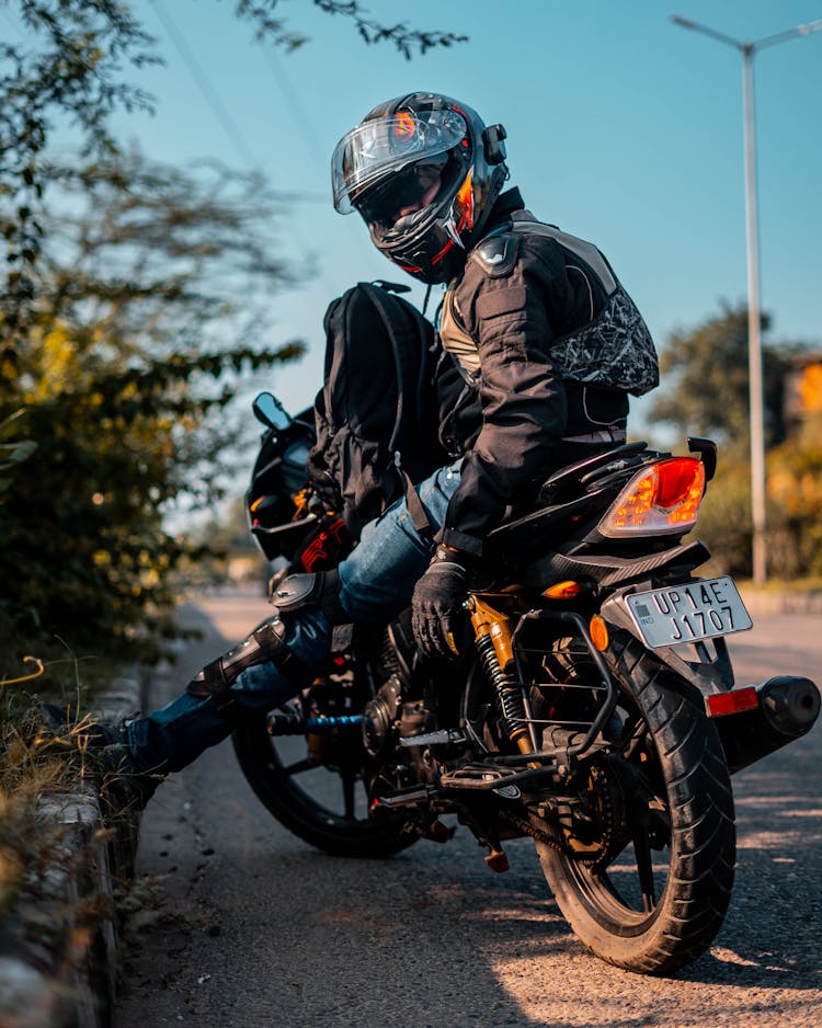 Motorcyclist Wearing Suit And Helmet Sitting On Motor