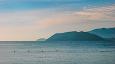 黎明时分，晴朗的天空下，远处的山脉映衬着宁静的海景