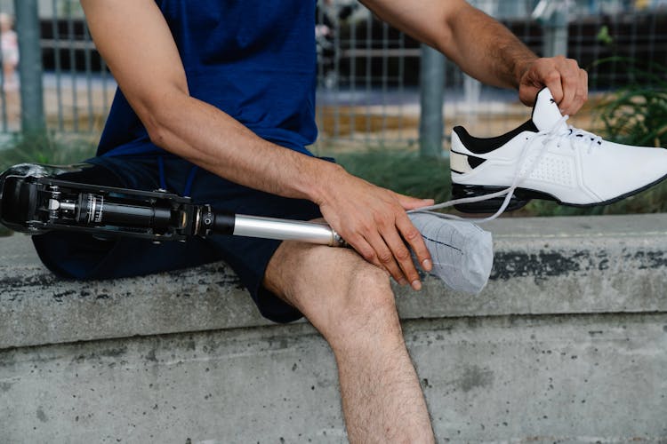 Person Removing Sports Shoe On A Prosthetic Leg