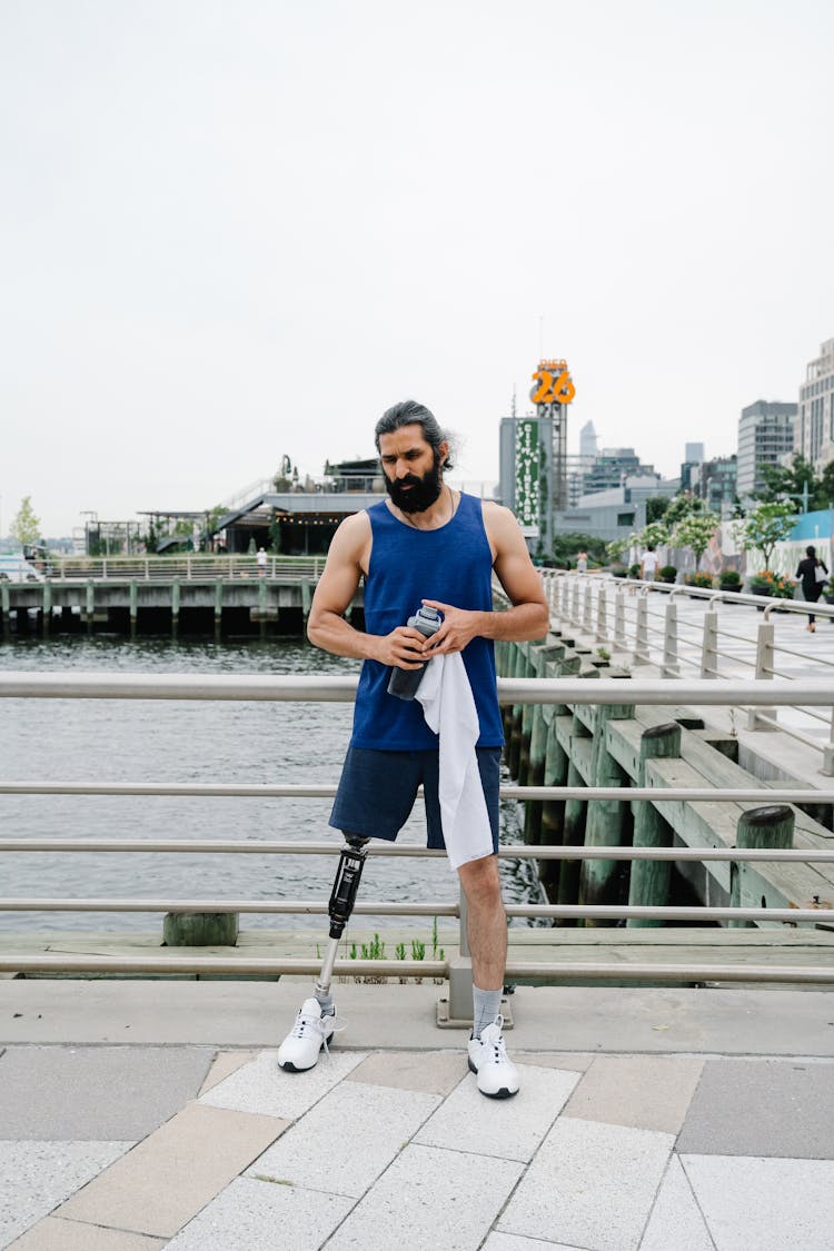 Man In Sportswear And With Prosthetic Leg Standing By The River 