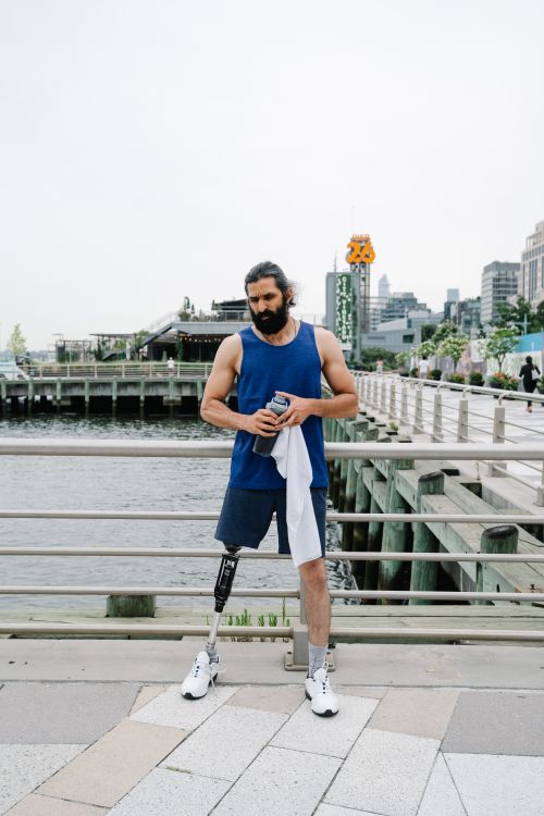 Free A man with a prosthetic leg stands confidently by the waterfront, embodying strength and resilience. Stock Photo