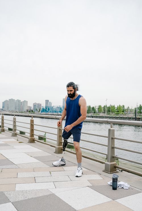 Free Amputee man with prosthetic leg working out by the river, promoting body positivity and fitness. Stock Photo