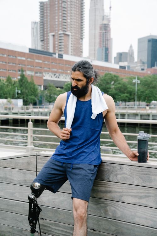 Free Man with a prosthetic leg relaxing outdoors in an urban setting, embodying fitness and resilience. Stock Photo