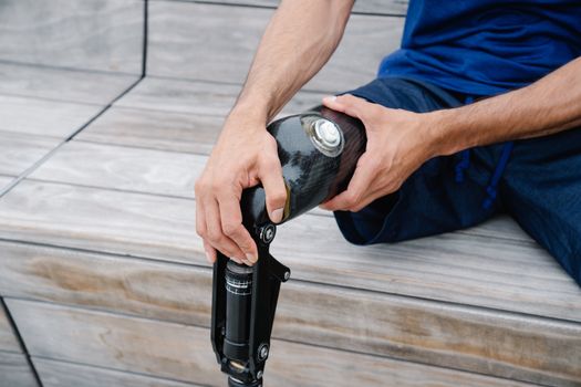 An adult adjusting their prosthetic leg outdoors, highlighting body positivity and disability representation.