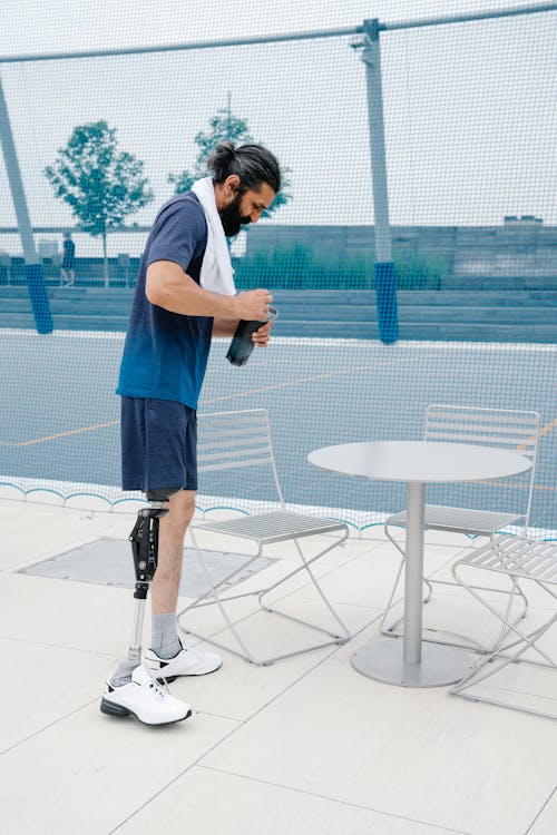 Male Amputee standing beside Chairs