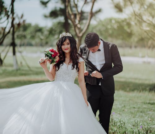Женщина в свадебном платье держит цветок с мужчиной в черном пиджаке