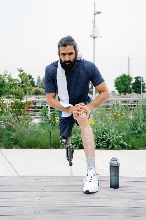 Free A man with a prosthetic leg stretches outdoors, focusing on fitness and health. Stock Photo