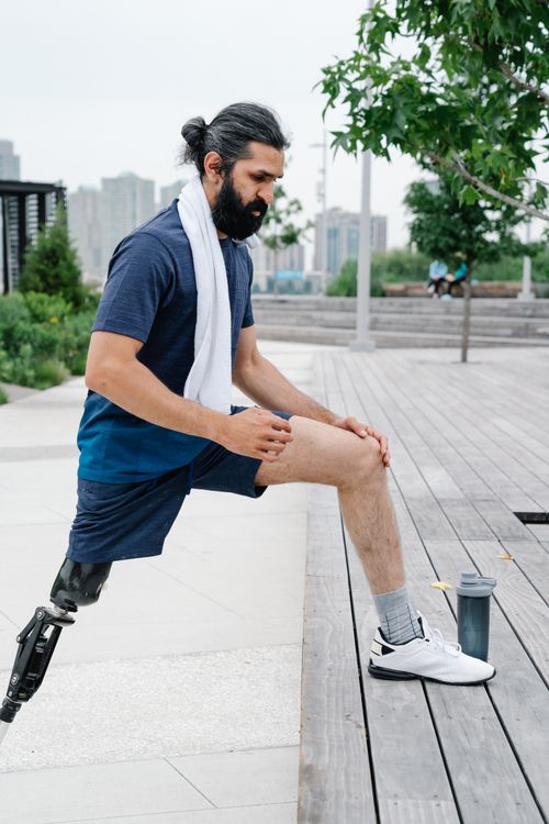 Free A man with a prosthetic leg stretches before exercise, promoting fitness and inclusivity. Stock Photo