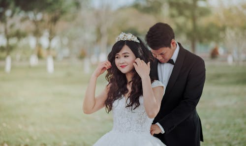 бесплатная Жених связывает белое кружевное свадебное платье невесты сзади Стоковое фото