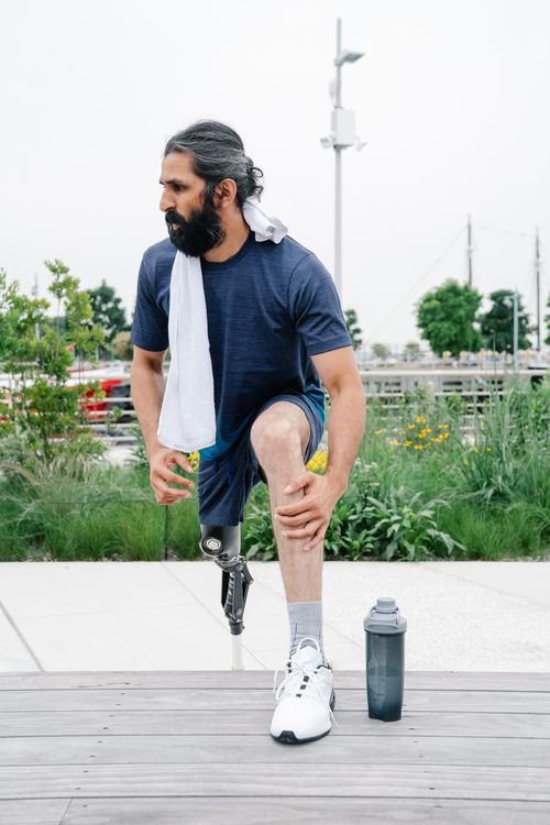 Free A man with a prosthetic leg stretching outdoors, promoting fitness and body positivity. Stock Photo