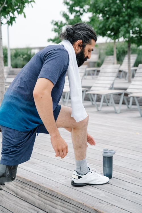 Free A man with a prosthetic leg stretches outdoors. Fitness and determination. Stock Photo