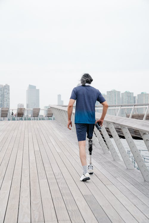 Back View of Man with Prosthetic Leg walking on Footbridge 