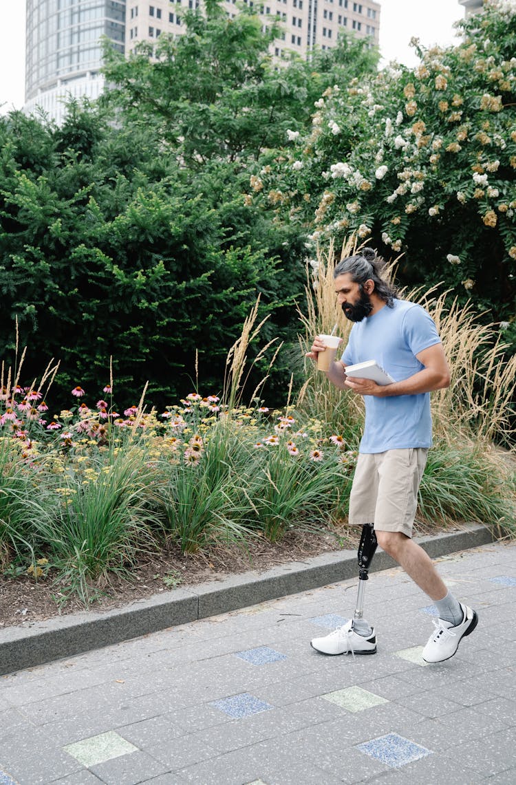 Man With Prosthetic Leg Walking While Drinking Coffee