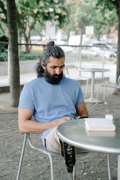 Man with Prosthetic Leg sitting on a Chair on a Park 