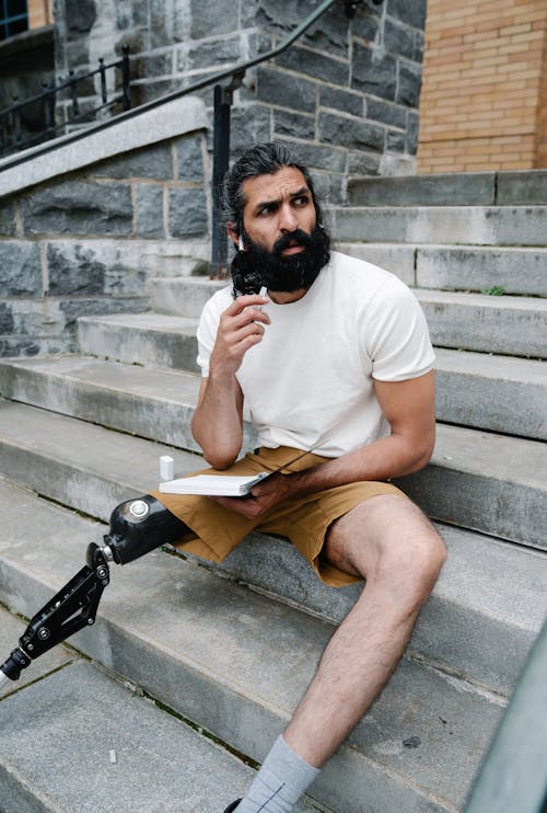 Man with Prosthetic Leg seated on Staircase