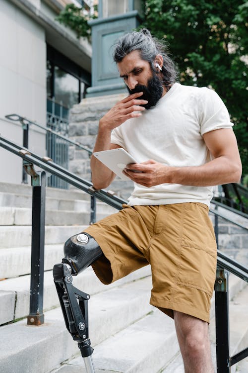 Man with Prosthetic Leg standing on Stairs reading Book 