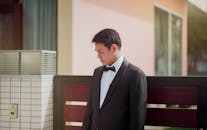 一位穿着燕尾服的时尚年轻人站在一栋现代建筑的户外