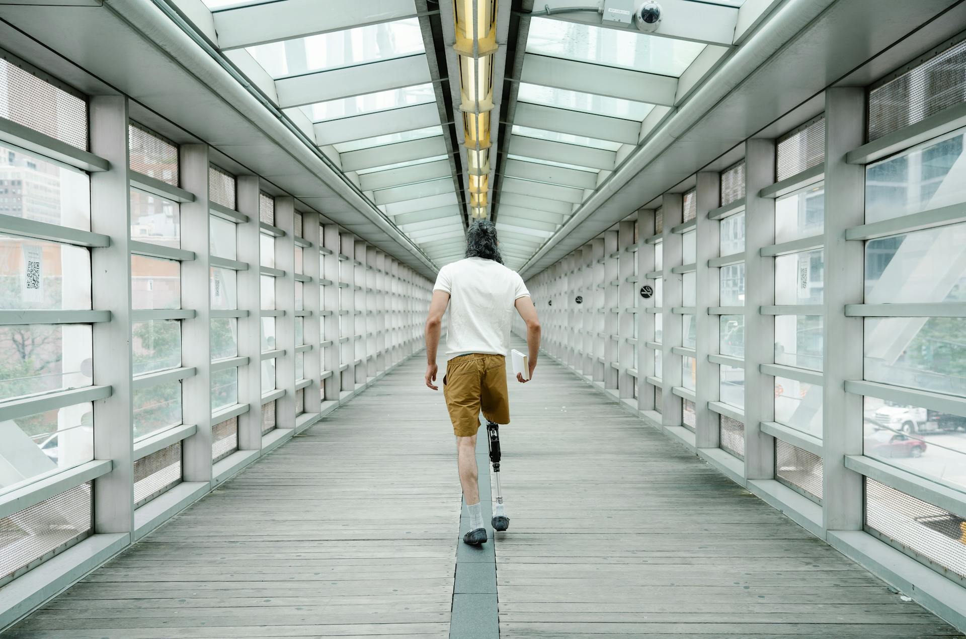 Man with Prosthetic Leg walking inside Footbridge 