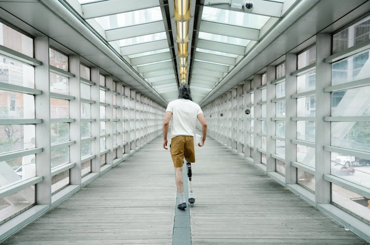 Man With Prosthetic Leg Walking Inside Footbridge 