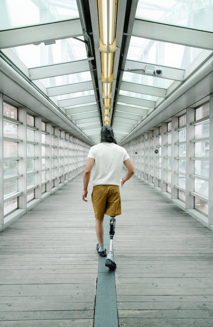 Man With Prosthetic Leg Walking Inside Footbridge 