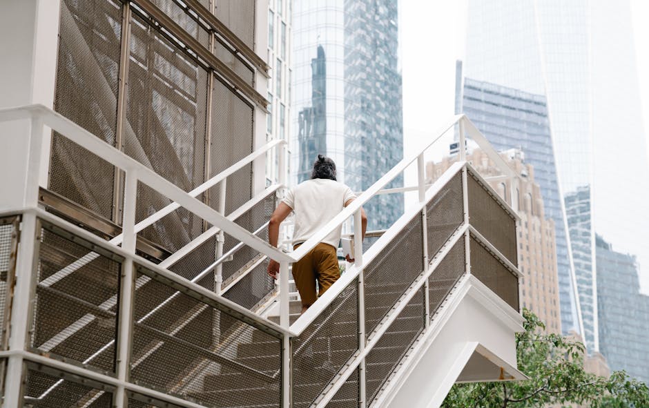 Individual walking up stairs with city skyscrapers in the background, urban scene.