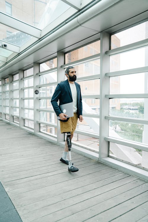 Man walking with a Prosthetic Leg carrying Laptop