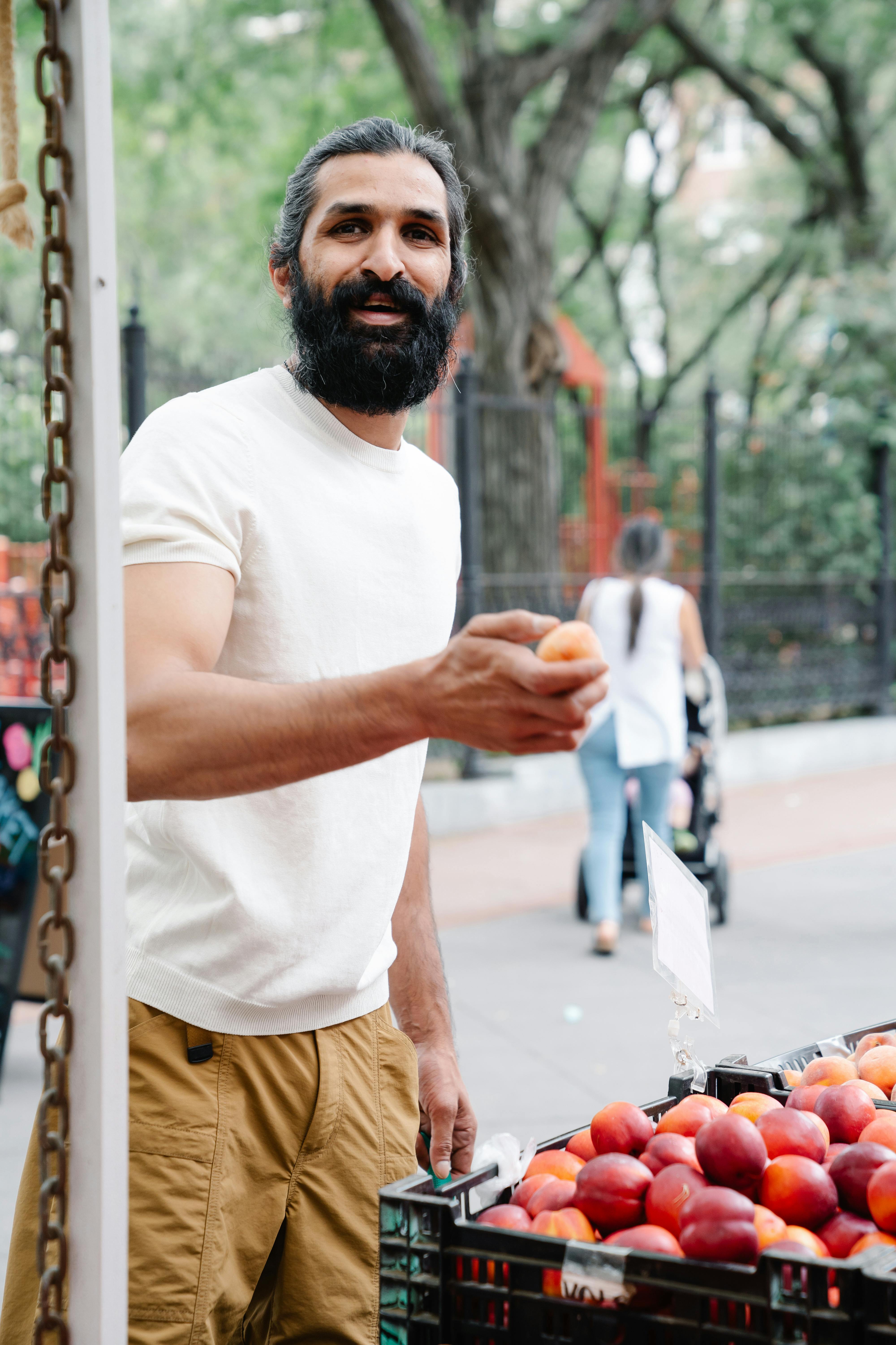 man with beard holding fruit in hand