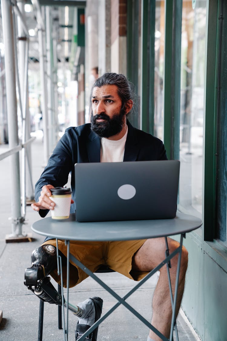 Man With Prosthetic Leg Sitting In Front Of Laptop 