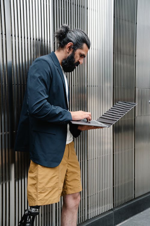 Man with Prosthetic Leg using Laptop while Standing