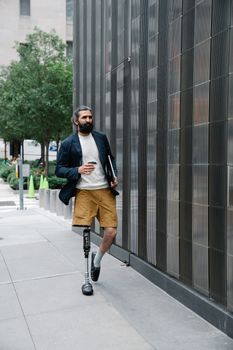 A man with a prosthetic leg walking confidently outdoors, showcasing body positivity and independence.
