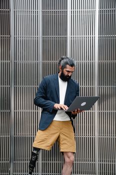 A man with a prosthetic leg working on a laptop, showcasing inclusivity and modern professionalism.