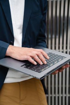 Close-up of a business person typing on a laptop outside. Ideal for technology and work themes.
