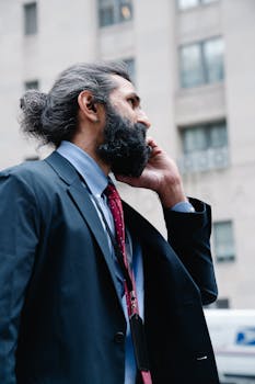 Confident businessman in formal attire having a phone conversation on a city street.