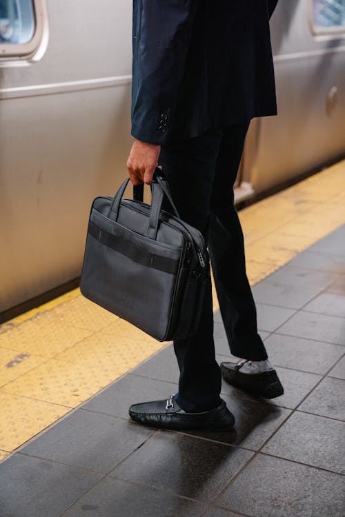 站在地鐵站台上提著手提箱的男人