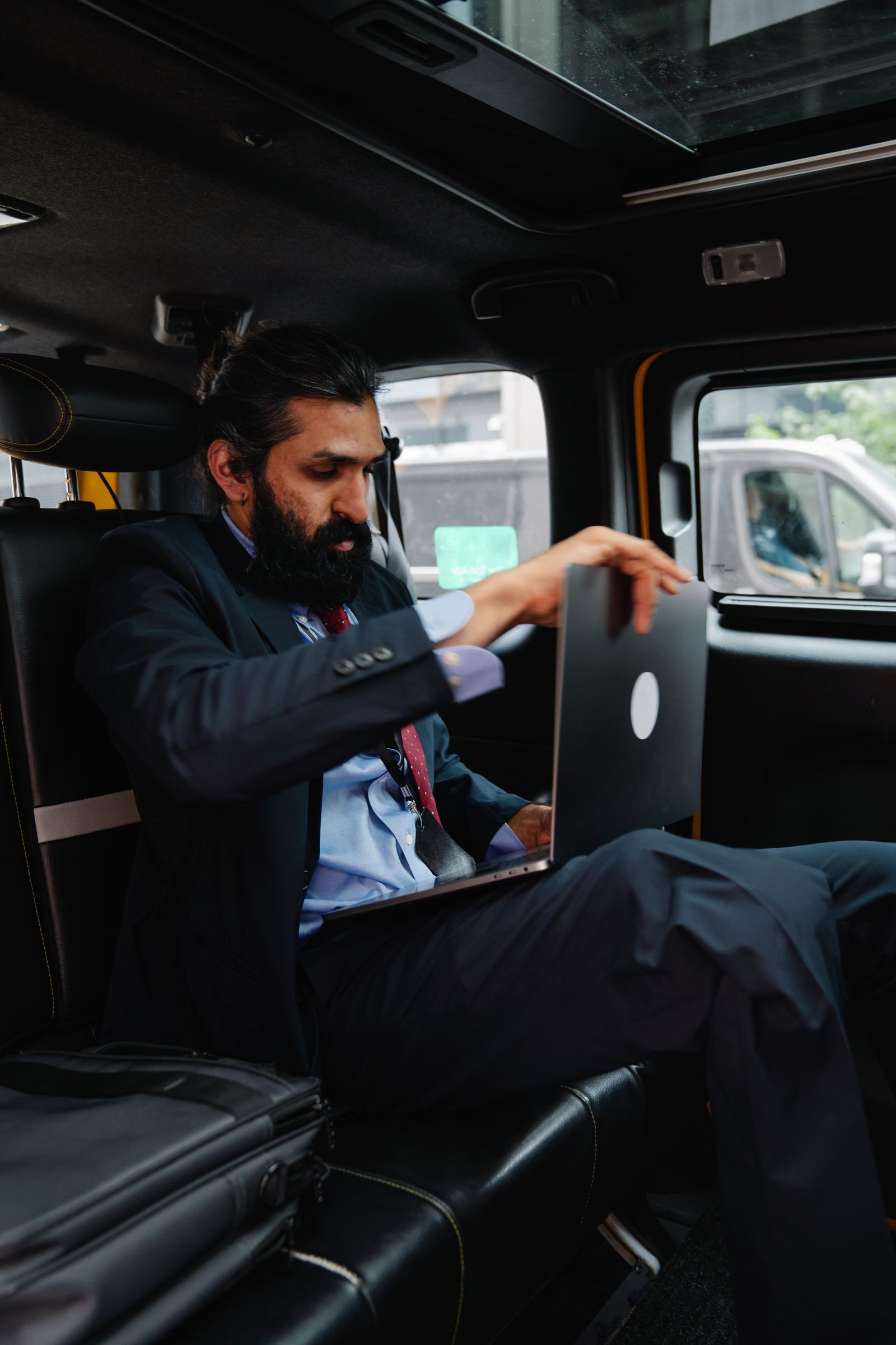 Professional using a laptop inside a car representing work-related travel between workplaces in Australia