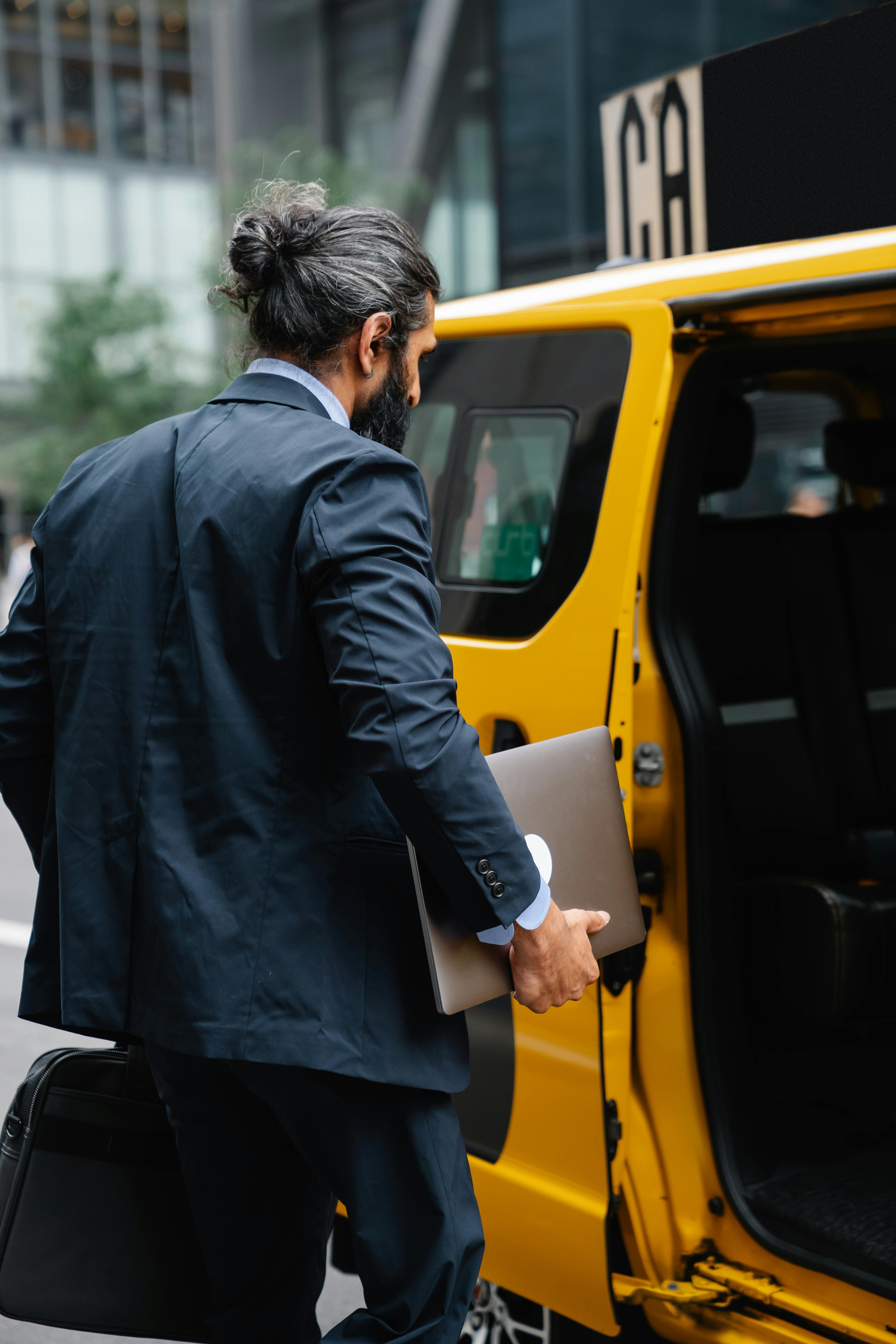 man with a laptop getting into the taxi