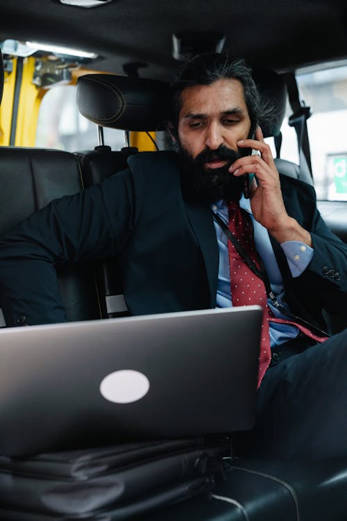 Businessman talking on Phone while looking at his Laptop 