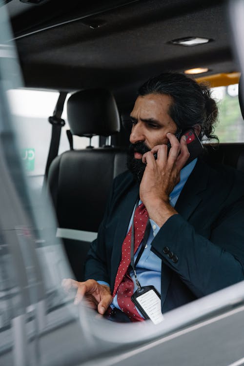 Man in Suit sitting inside Car talking on Phone