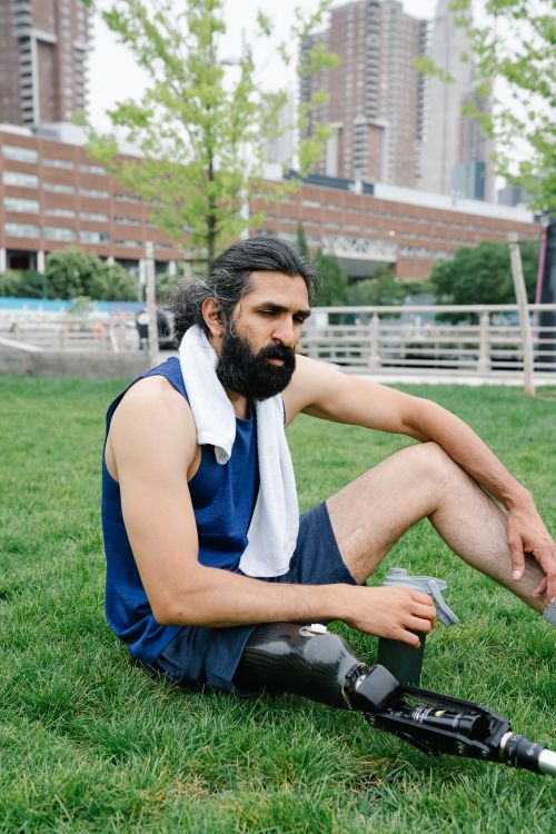 Free Bearded man with prosthetic leg resting outdoors in city park, embracing body positivity. Stock Photo