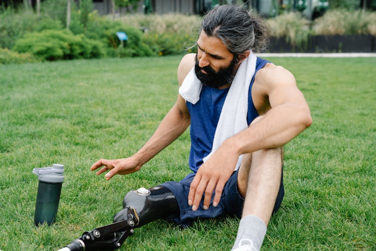 Man With Prosthetic Limb Resting On Grass 