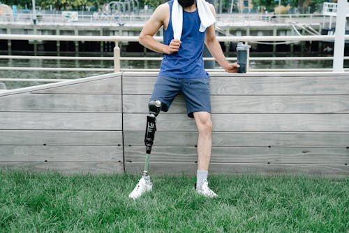 Free Man with Prosthetic Leg leaning on Wooden Wall Stock Photo