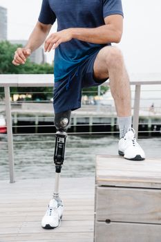 Man with prosthetic leg exercising outdoors, emphasizing body positivity and resilience.