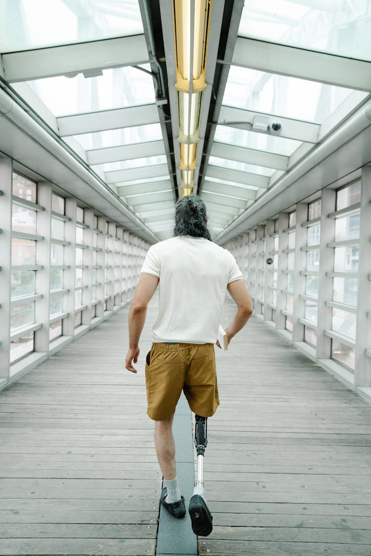 Man With Prosthetic Leg Walking On A Wooden Footpath 