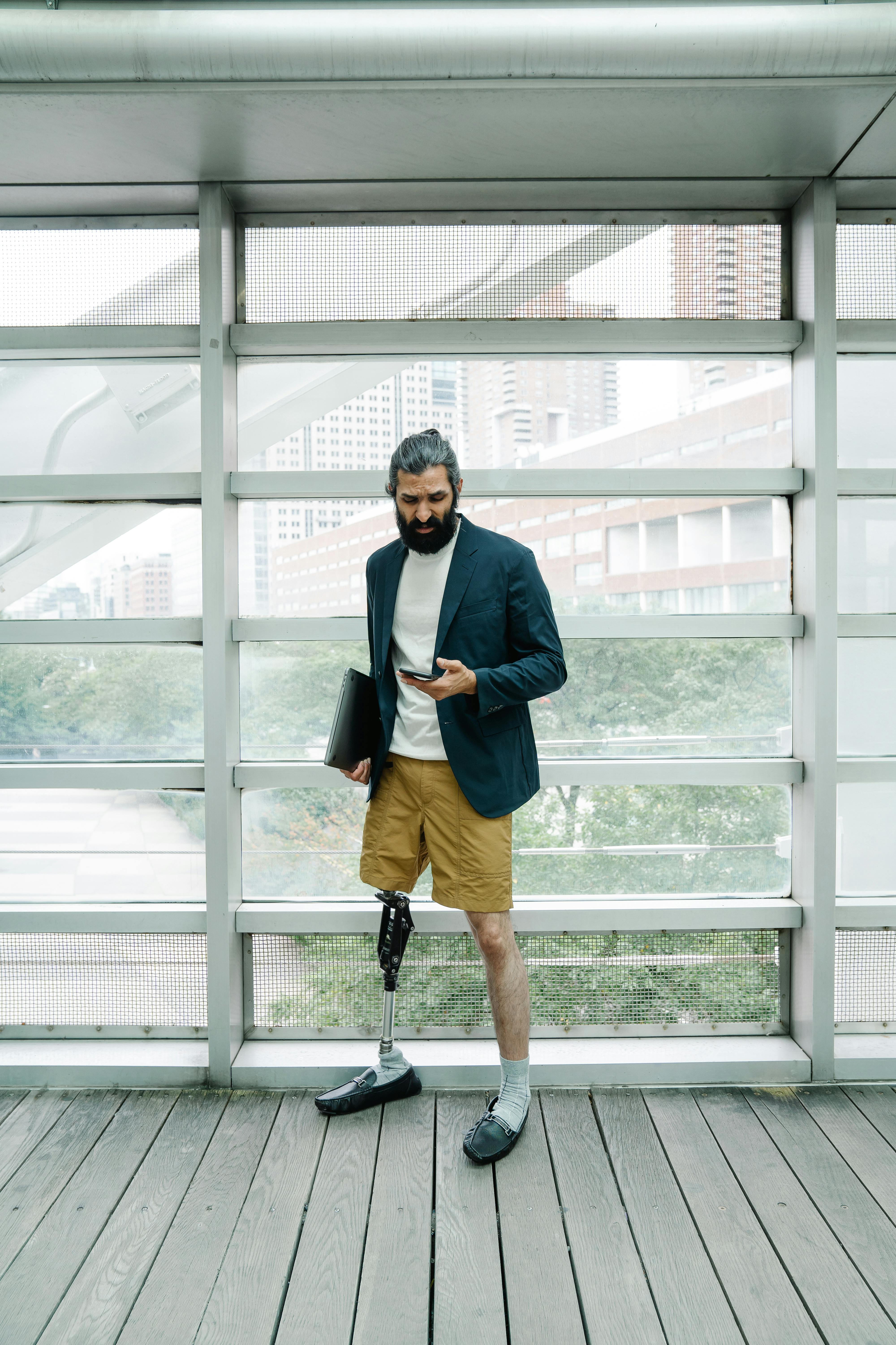 man with prosthetic leg looking at his phone