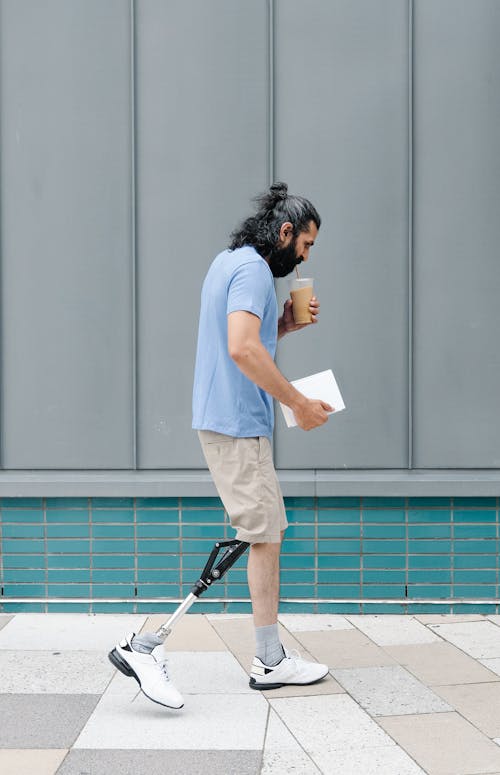 Man with Prosthetic Limb walking while drinking Iced Coffee