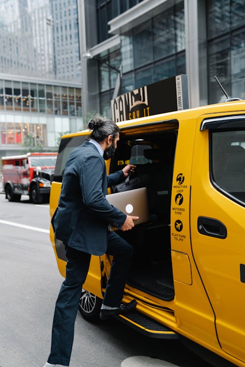 Uomo D'affari Che Entra In Taxi E Tiene In Mano Un Laptop