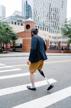 A man with a prosthetic leg walking across a city street, showcasing resilience and modern urban lifestyle.